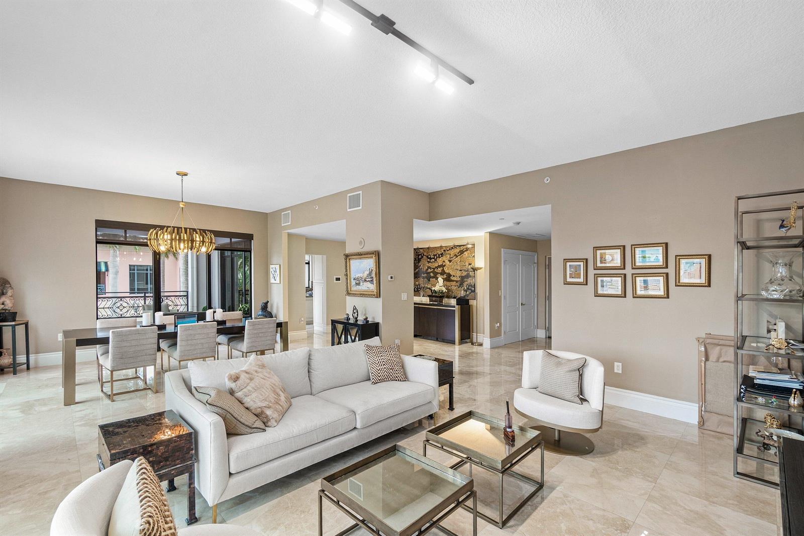A spacious living and dining area features neutral walls, marble floors, and modern track lighting — 200 E Palmetto Park Road # 22, Boca Raton FL 33432, BOCA RATON, FL