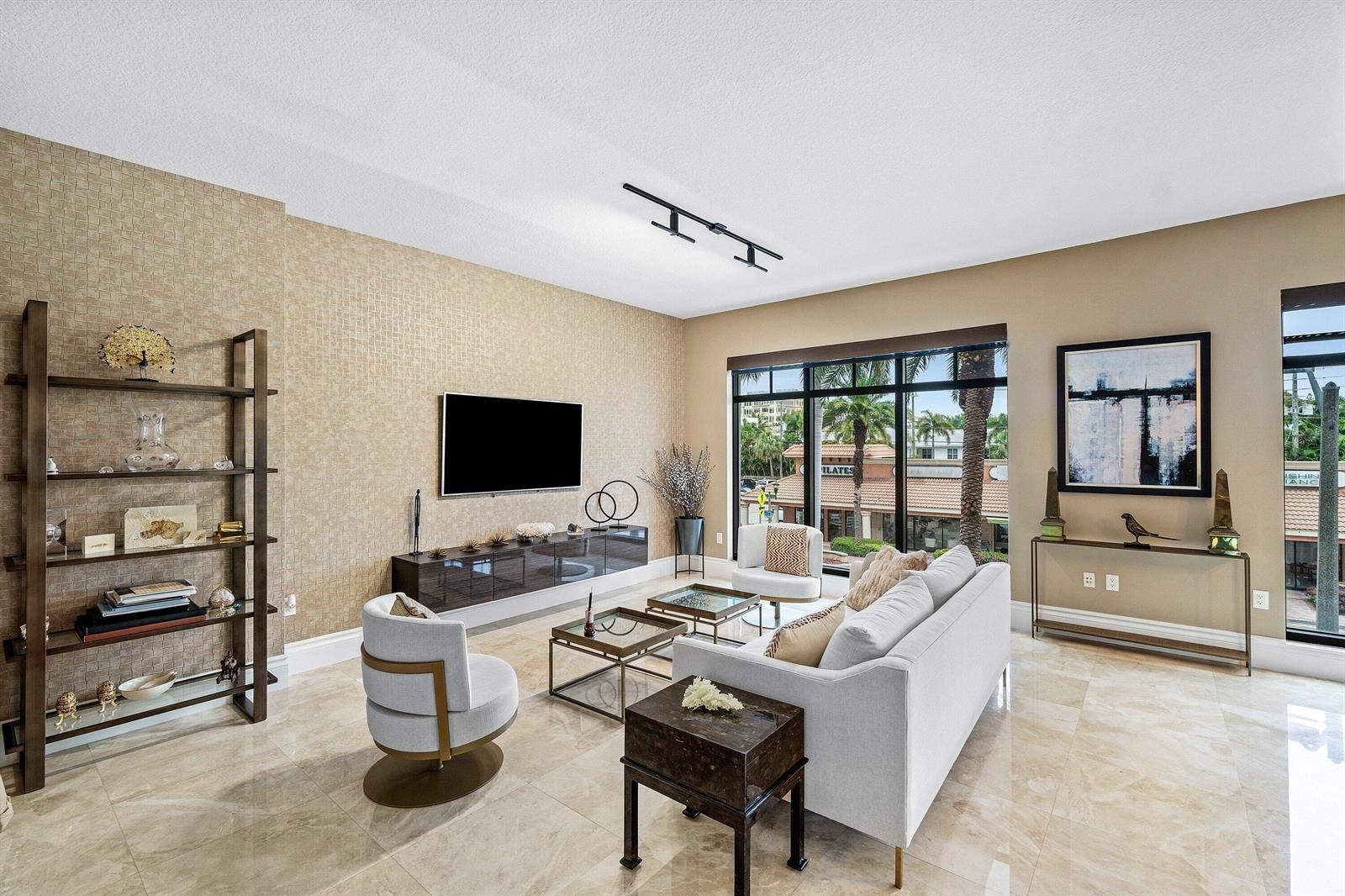 A modern living room features a textured accent wall, light tile flooring, and large windows — 200 E Palmetto Park Road # 22, Boca Raton FL 33432, BOCA RATON, FL