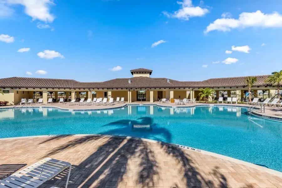 A swimming pool with a brick deck sits in front of a large clubhouse building — 17220 HARVEST MOON WAY, BRADENTON, FL