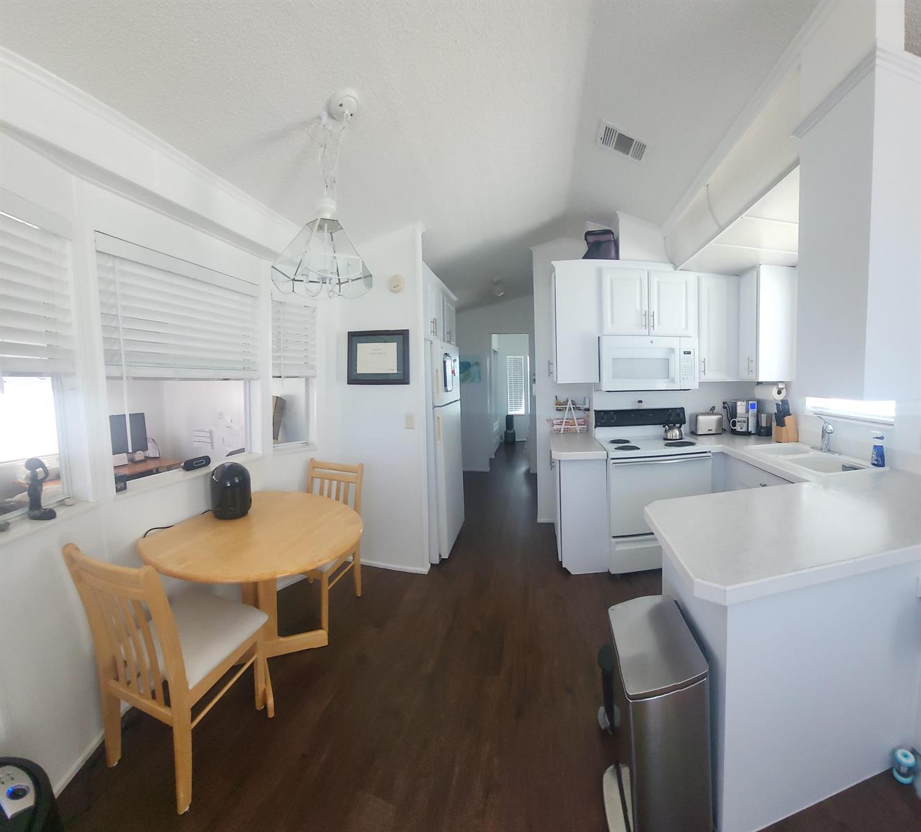 A bright kitchen and dining area features white cabinetry, dark wood flooring, and a table — 900 Juno Ocean Walk # 37, Juno Beach FL 33408, JUNO BEACH, FL
