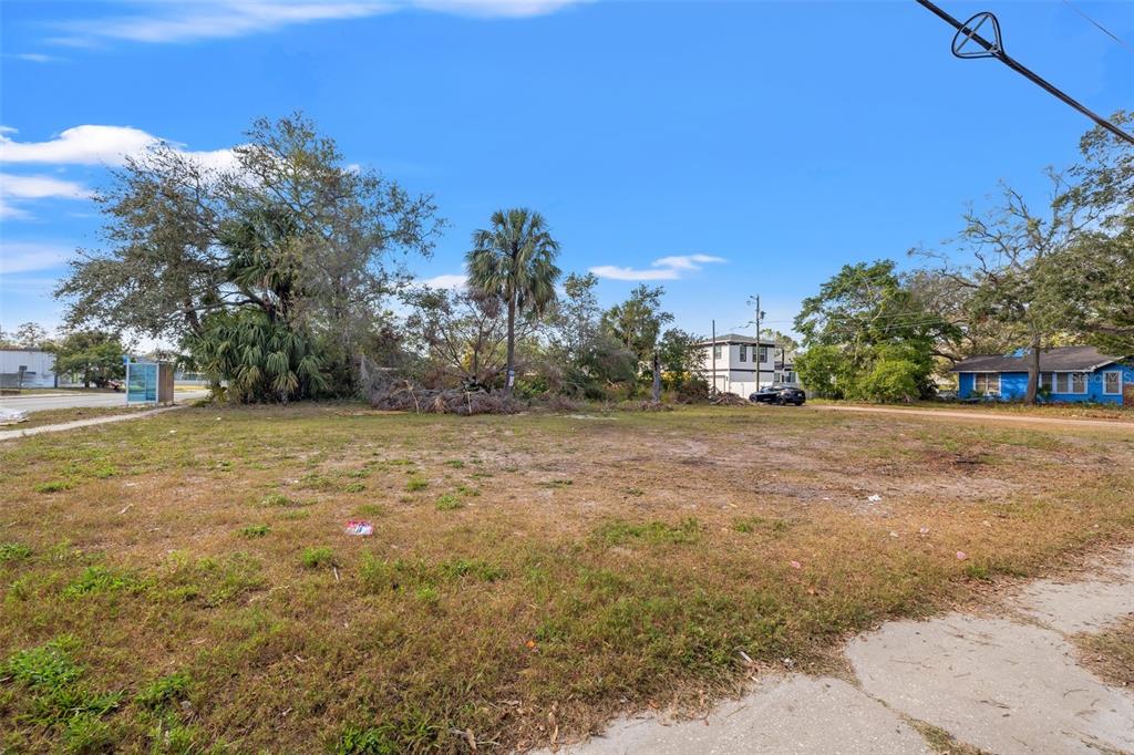 A vacant, grassy lot with scattered trees and a blue house in the background — 28TH STREET S, ST PETERSBURG, FL