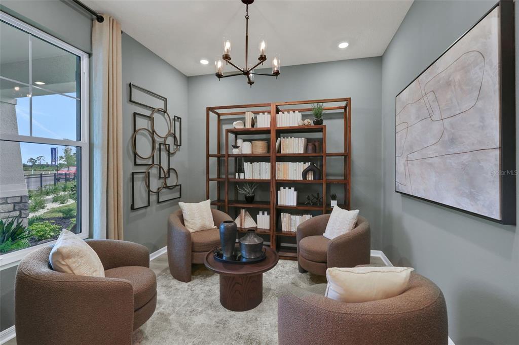 A sitting room features four brown armchairs, a central coffee table, and a large bookshelf — 17297 COTTONTAIL CIRCLE, PUNTA GORDA, FL