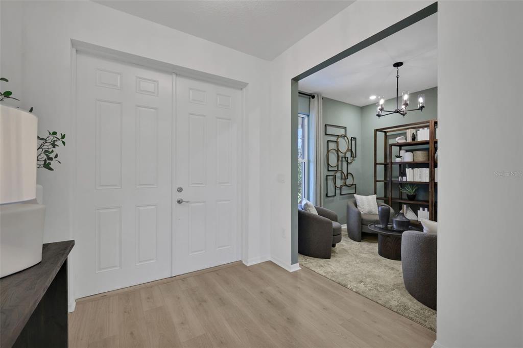 A foyer with light wood flooring leads into a sitting room with dark armchairs — 17297 COTTONTAIL CIRCLE, PUNTA GORDA, FL