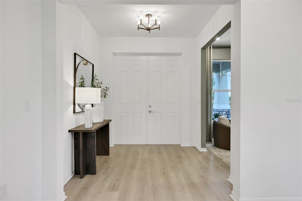 A bright entryway features white double doors, a wooden console table, and light wood flooring — 17297 COTTONTAIL CIRCLE, PUNTA GORDA, FL