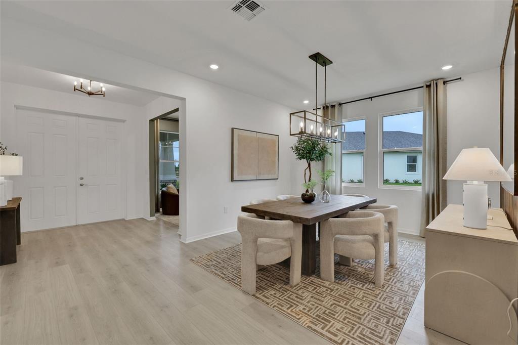 A dining room with a wooden table, upholstered chairs, a geometric rug, and pendant lighting — 17297 COTTONTAIL CIRCLE, PUNTA GORDA, FL