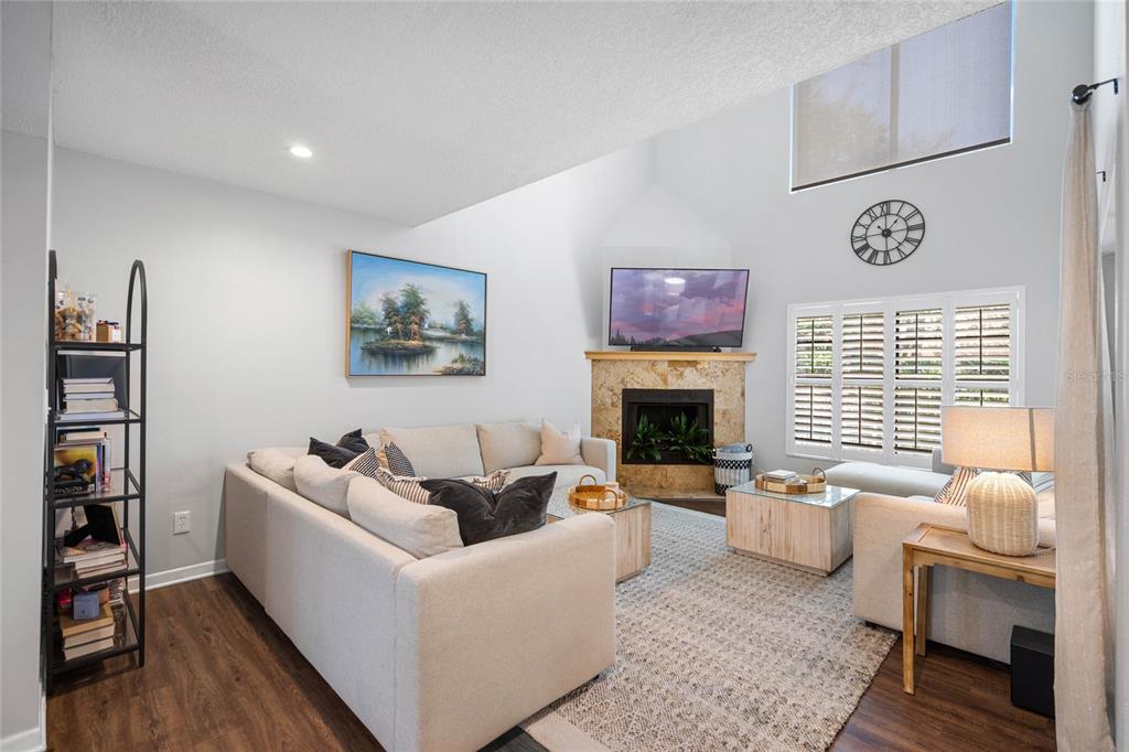 A living room features a stone fireplace, vaulted ceilings, and a sectional sofa — 1092 SANABEL COURT NE, ST PETERSBURG, FL