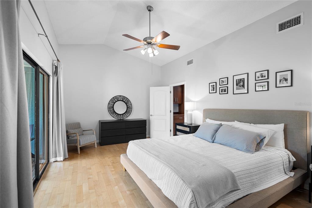 A bedroom features a vaulted ceiling, a ceiling fan, a bed, and a black dresser — 1092 SANABEL COURT NE, ST PETERSBURG, FL