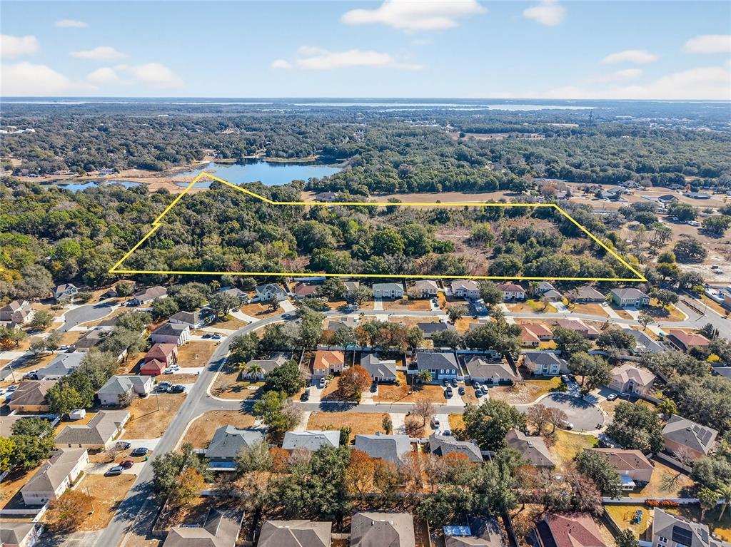 An aerial view shows a large, wooded plot of land outlined in yellow near residential homes — MYRTLE LAKE AVENUE, FRUITLAND PARK, FL