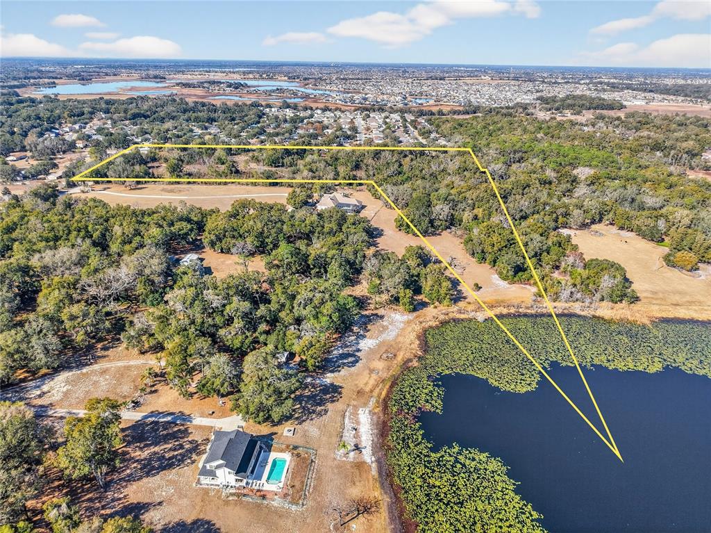 An aerial view shows a house with a pool and a large, wooded waterfront lot — MYRTLE LAKE AVENUE, FRUITLAND PARK, FL