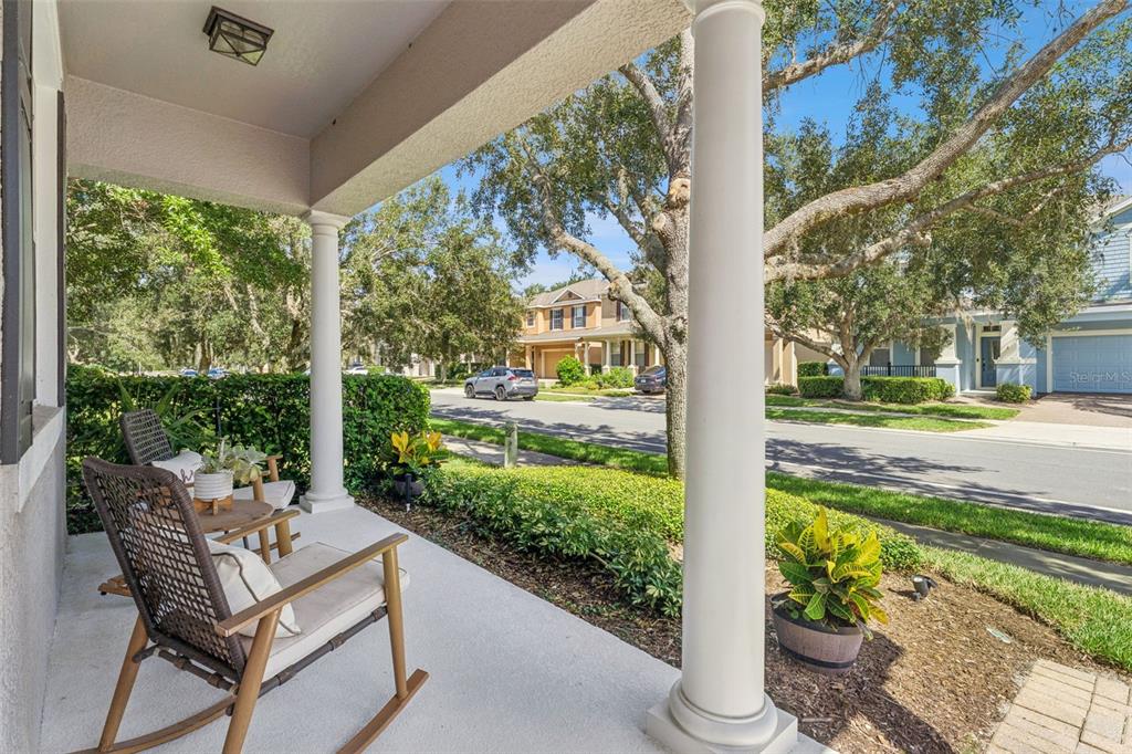 A covered front porch features two rocking chairs, white columns, and a view of the street — 629 LEGACY PARK DRIVE, CASSELBERRY, FL