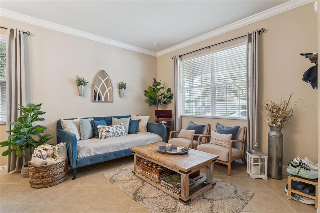 A living room features a blue sofa, two armchairs, a wooden coffee table, and windows — 629 LEGACY PARK DRIVE, CASSELBERRY, FL