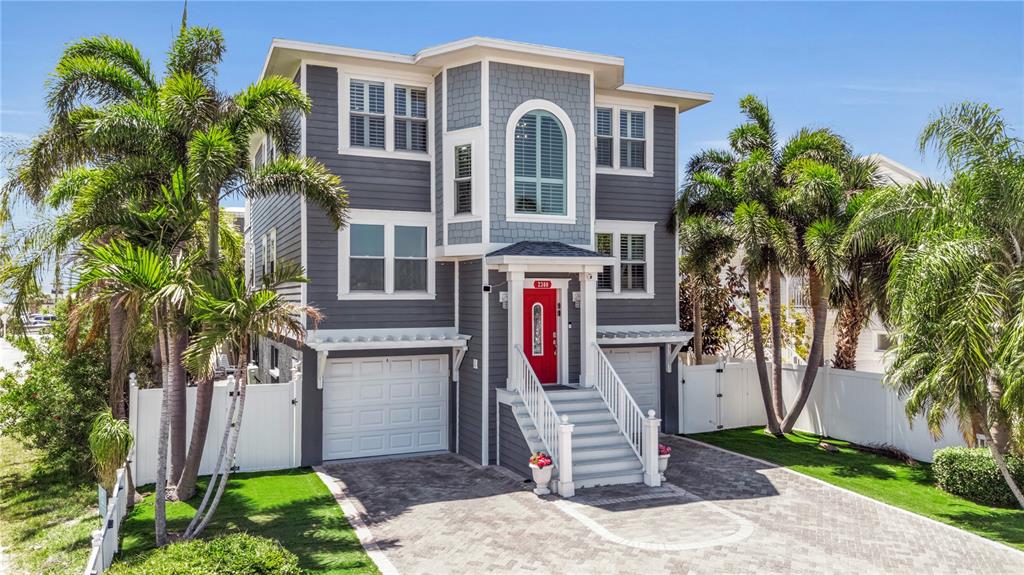 A three-story gray house with a red front door and a paved driveway — 2300 AVENUE B, BRADENTON BEACH, FL
