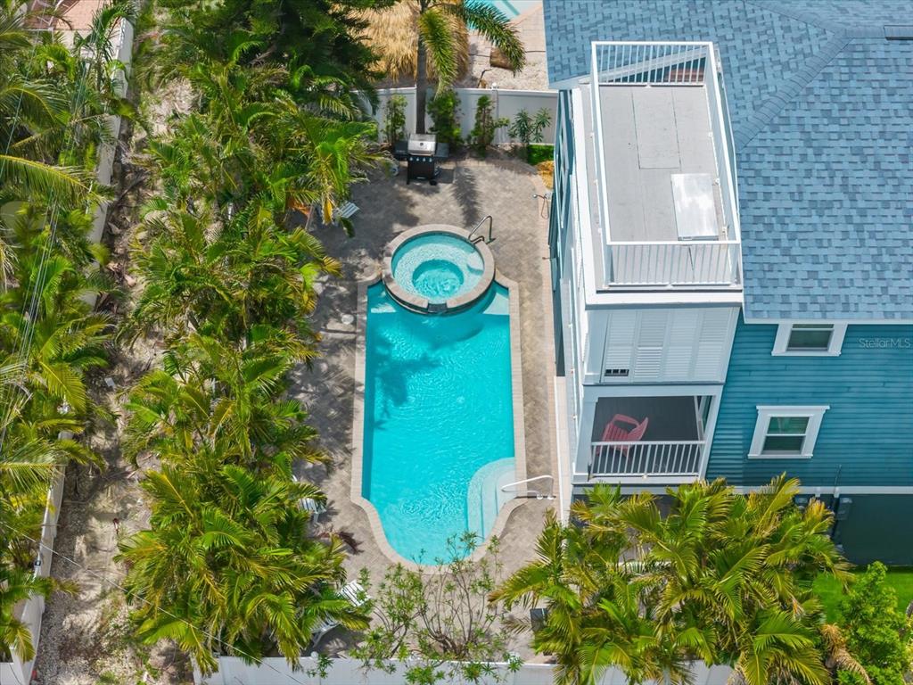 An aerial view of a backyard featuring a swimming pool, integrated spa, and patio area — 2300 AVENUE B, BRADENTON BEACH, FL