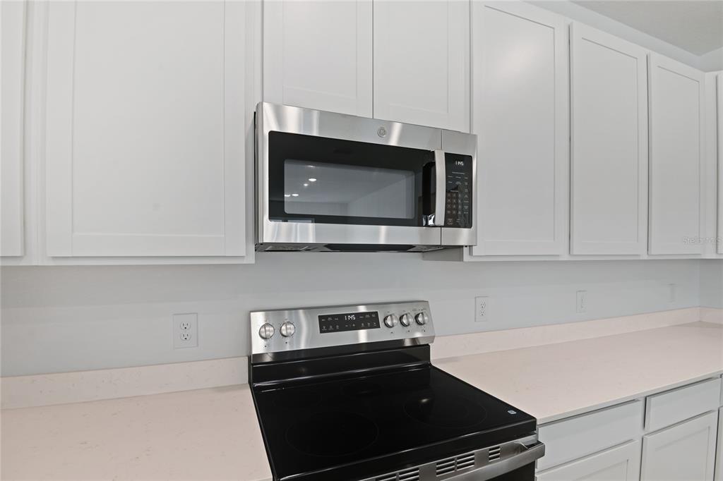 A kitchen features white cabinets, a stainless steel microwave, and a black electric range — 5163 KINSLEY DRIVE, WINTER HAVEN, FL