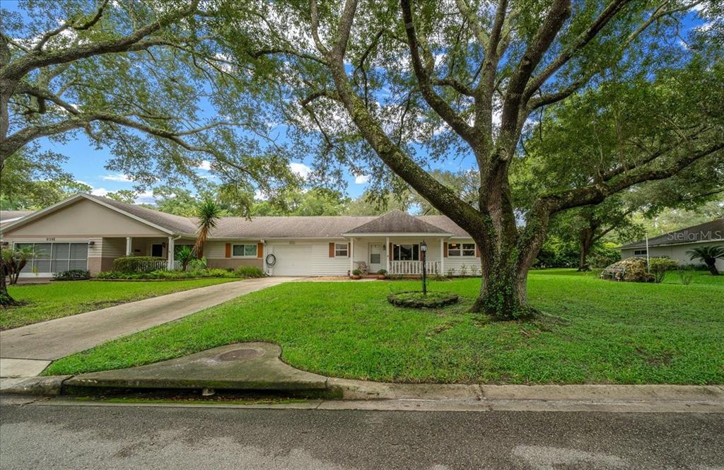 A single-story house with a white exterior, a large front tree, and a concrete driveway — 8720 SW 97TH STREET UNIT F, OCALA, FL