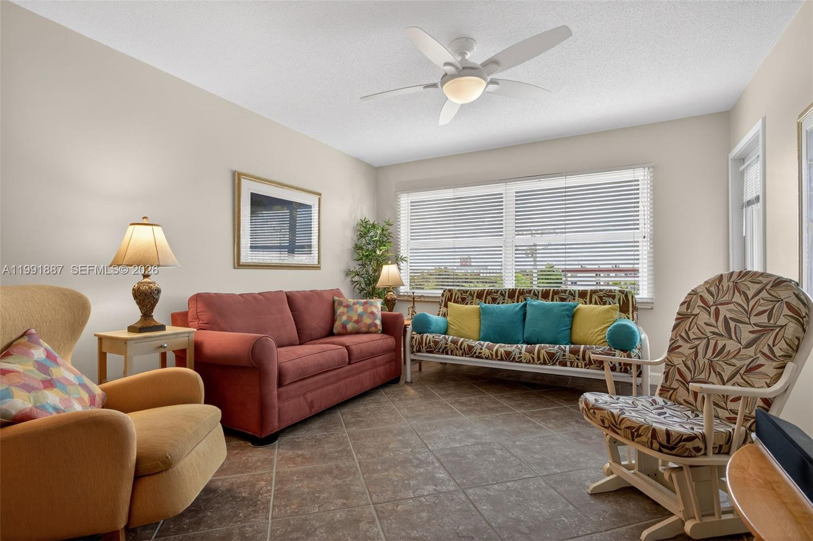A living room features tile flooring, a ceiling fan, and a variety of seating furniture — 4299 NW 16th St # 310, Lauderhill FL 33313, LAUDERHILL, FL
