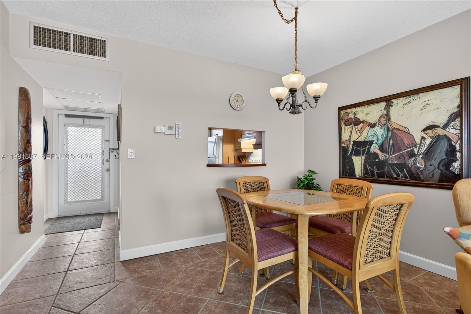 A dining area features a wooden table, four chairs, a chandelier, and a wall painting — 4299 NW 16th St # 310, Lauderhill FL 33313, LAUDERHILL, FL