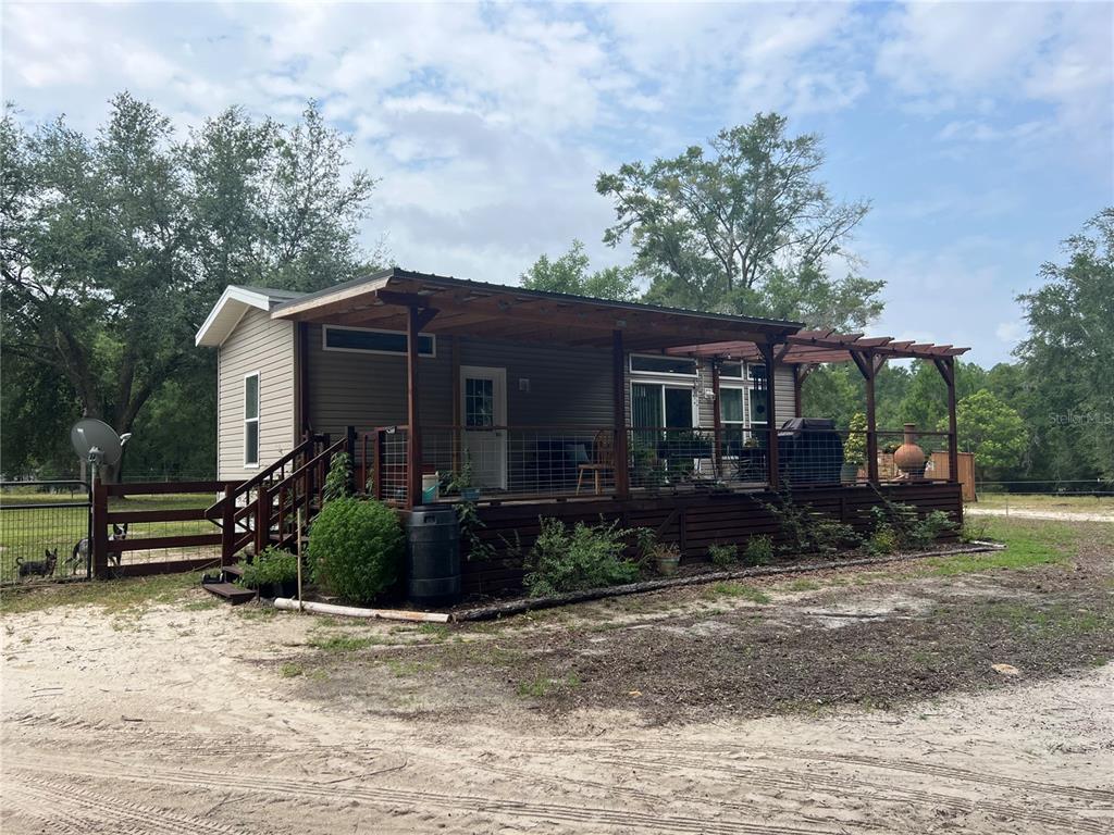 A single-story house with a large wooden deck and covered porch sits on a sandy lot — 3369 NE 53RD TERRACE, HIGH SPRINGS, FL