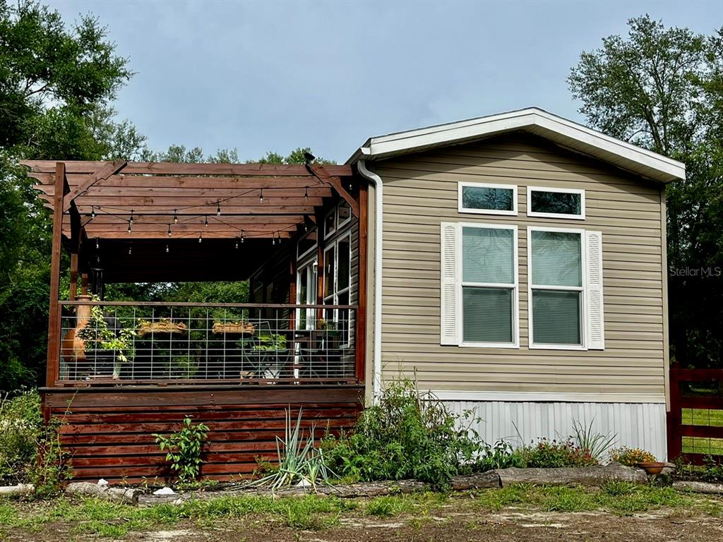 A mobile home with light siding features a wooden pergola over an attached outdoor deck — 3369 NE 53RD TERRACE, HIGH SPRINGS, FL