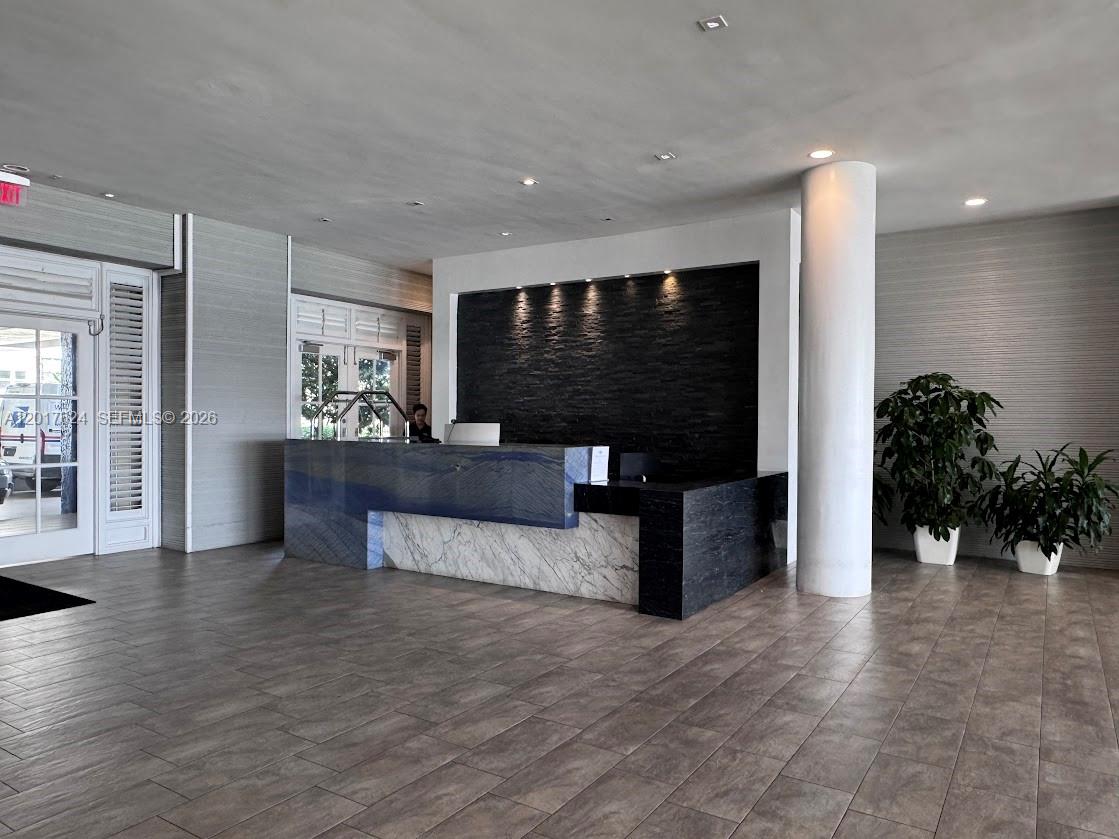 A modern lobby features a stone reception desk, a dark textured wall, and tile flooring — 800 West Ave # 441, Miami Beach FL 33139, MIAMI BEACH, FL