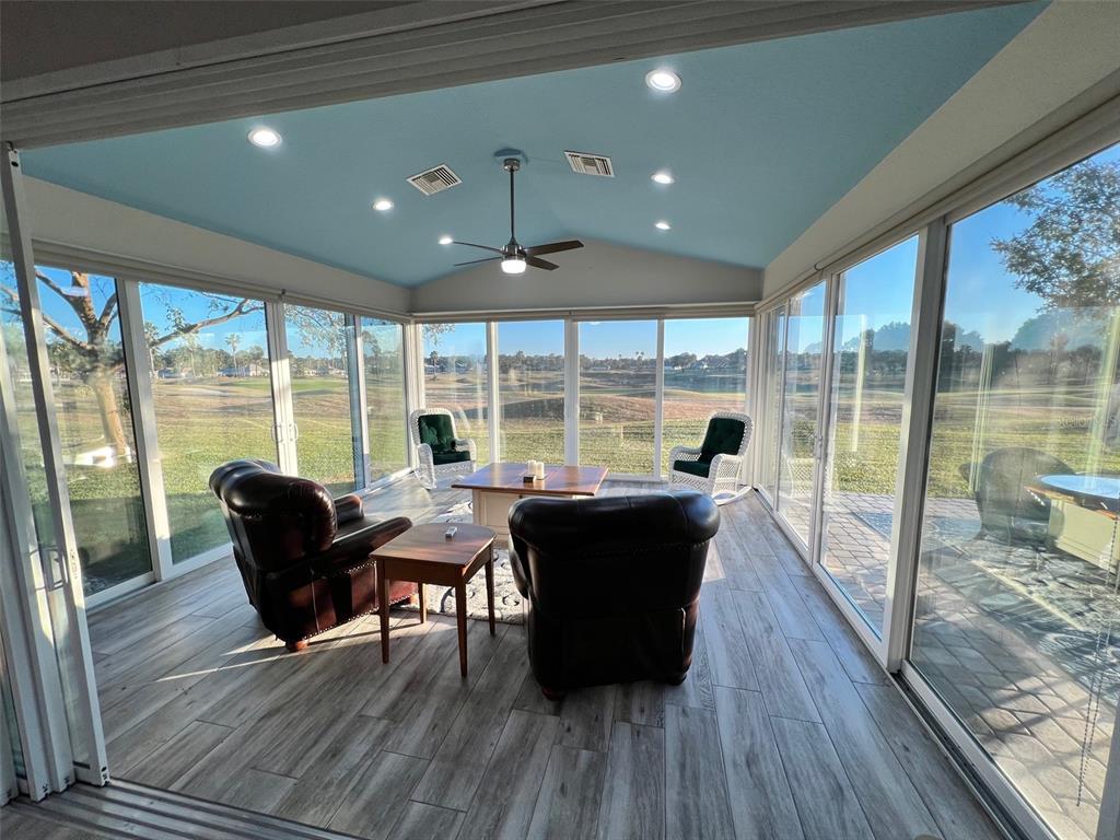A sunroom with wood-look tile floors, a blue ceiling, and large glass sliding doors — 9570 SE 136TH PLACE, SUMMERFIELD, FL