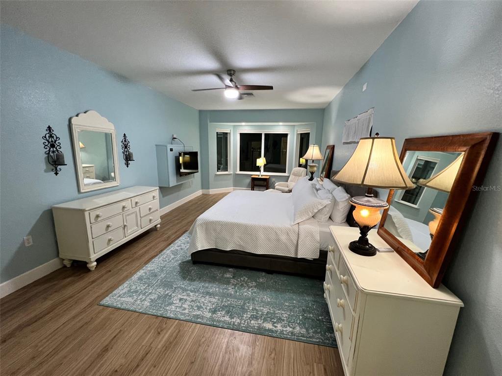 A bedroom features light blue walls, a white dresser, and a bed on a rug — 9570 SE 136TH PLACE, SUMMERFIELD, FL