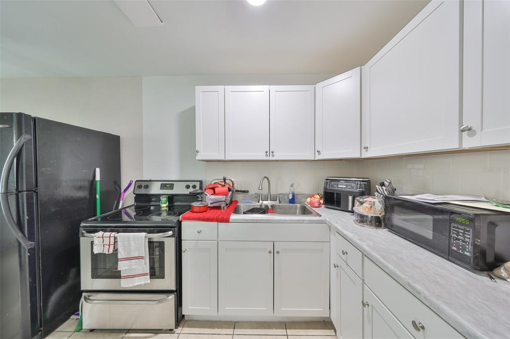 A kitchen with white cabinets, stainless steel appliances, a black refrigerator, and gray countertops — 11708 BALM RIVERVIEW ROAD, RIVERVIEW, FL