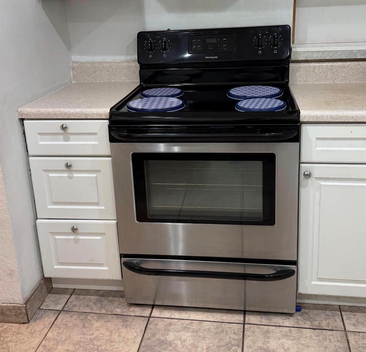 A stainless steel Frigidaire electric range is positioned between white cabinets and beige countertops — 4344 NW 9th Avenue # 3f, Pompano Beach FL 33064, POMPANO BEACH, FL