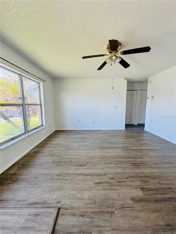 An empty room with wood-look flooring, a ceiling fan, and a large window — 37 LAS BRISAS WAY UNIT 37, KISSIMMEE, FL