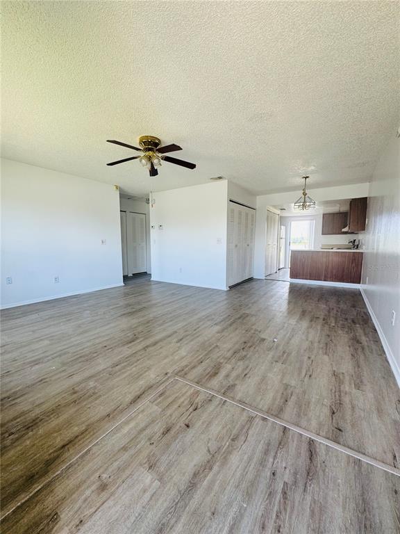 An open-concept living area features light wood-look flooring, white walls, and a ceiling fan — 37 LAS BRISAS WAY UNIT 37, KISSIMMEE, FL