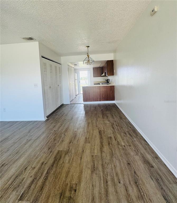 An open-concept living area with wood-look flooring leads to a kitchen with a breakfast bar — 37 LAS BRISAS WAY UNIT 37, KISSIMMEE, FL
