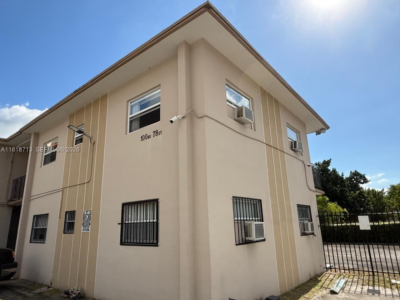 A two-story beige apartment building features window security bars and exterior wall-mounted air conditioning units — 100 NE 78th St # 9, Miami FL 33138, MIAMI, FL