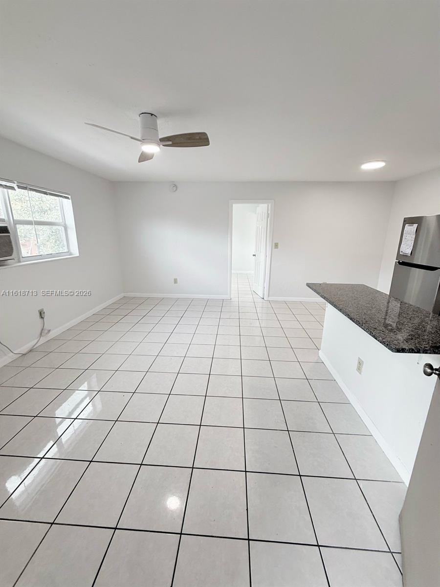 This room features white tile flooring, a ceiling fan, and an open kitchen counter — 100 NE 78th St # 9, Miami FL 33138, MIAMI, FL