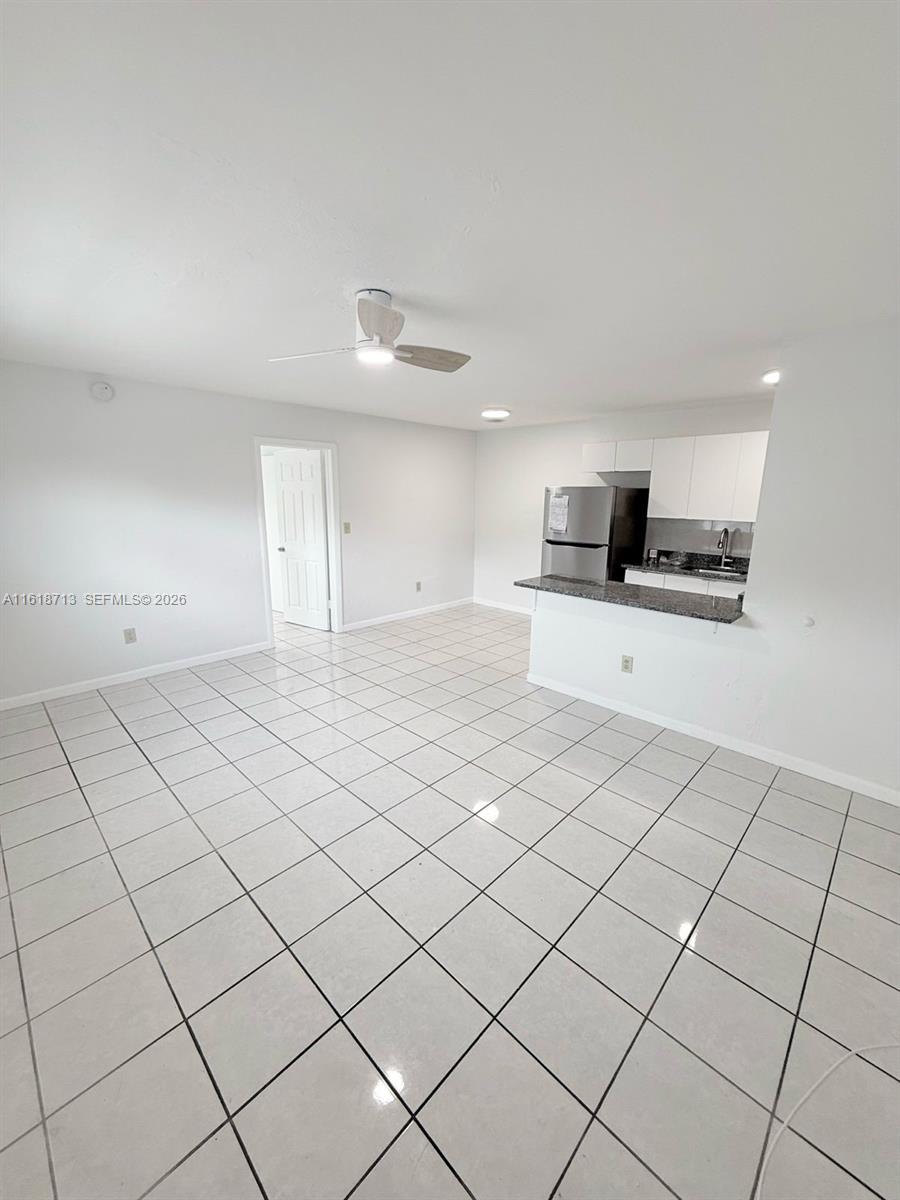 An open-concept room features white tile flooring, a ceiling fan, and a kitchen with granite countertops — 100 NE 78th St # 9, Miami FL 33138, MIAMI, FL