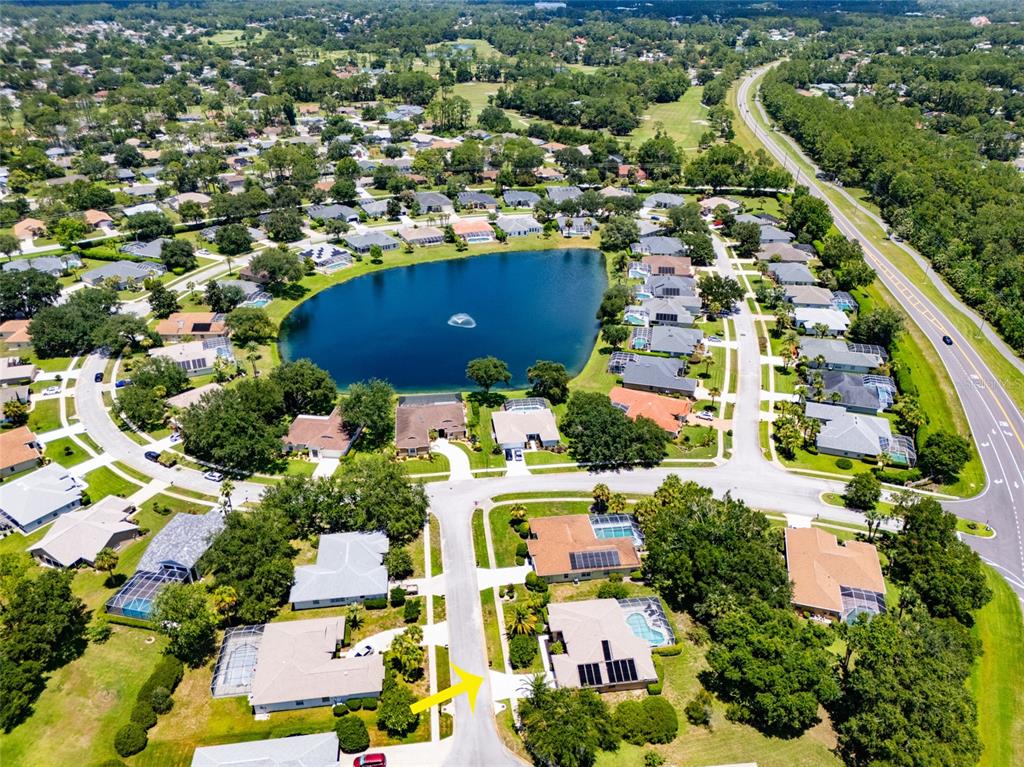 Aerial view of a suburban neighborhood featuring a central lake and a nearby highway — 5 FAIRFAX COURT, PALM COAST, FL