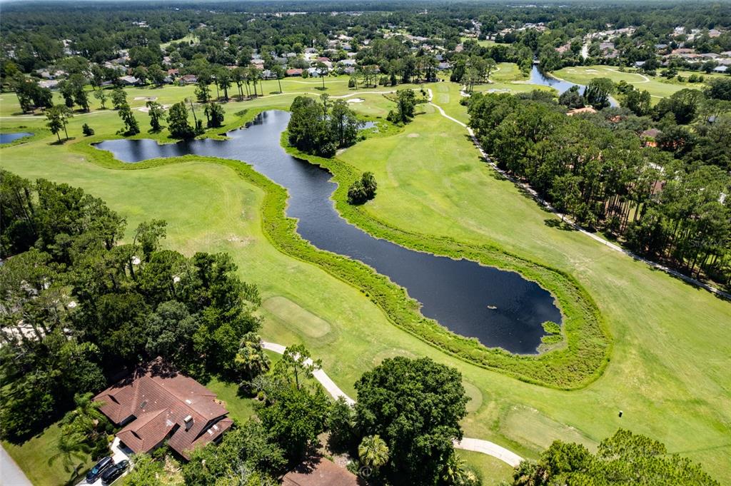 An aerial view shows a golf course with a large pond surrounded by green fairways — 5 FAIRFAX COURT, PALM COAST, FL