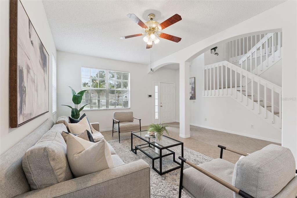 A living room features a grey sofa, glass coffee table, and a staircase with railings — 2008 CHAPMAN OAKS DRIVE, OVIEDO, FL