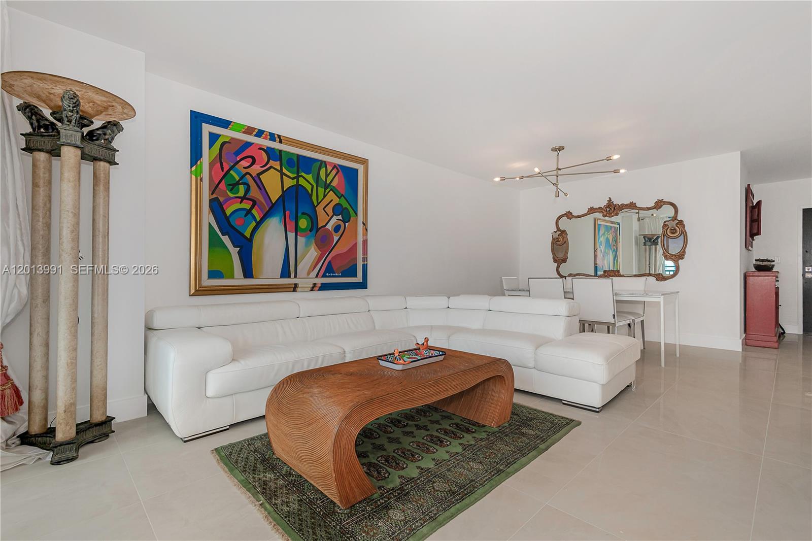 A living room features a white sectional sofa, a wooden coffee table, and colorful wall art — 90 ALTON RD # 1007, Miami Beach FL 33139, MIAMI BEACH, FL