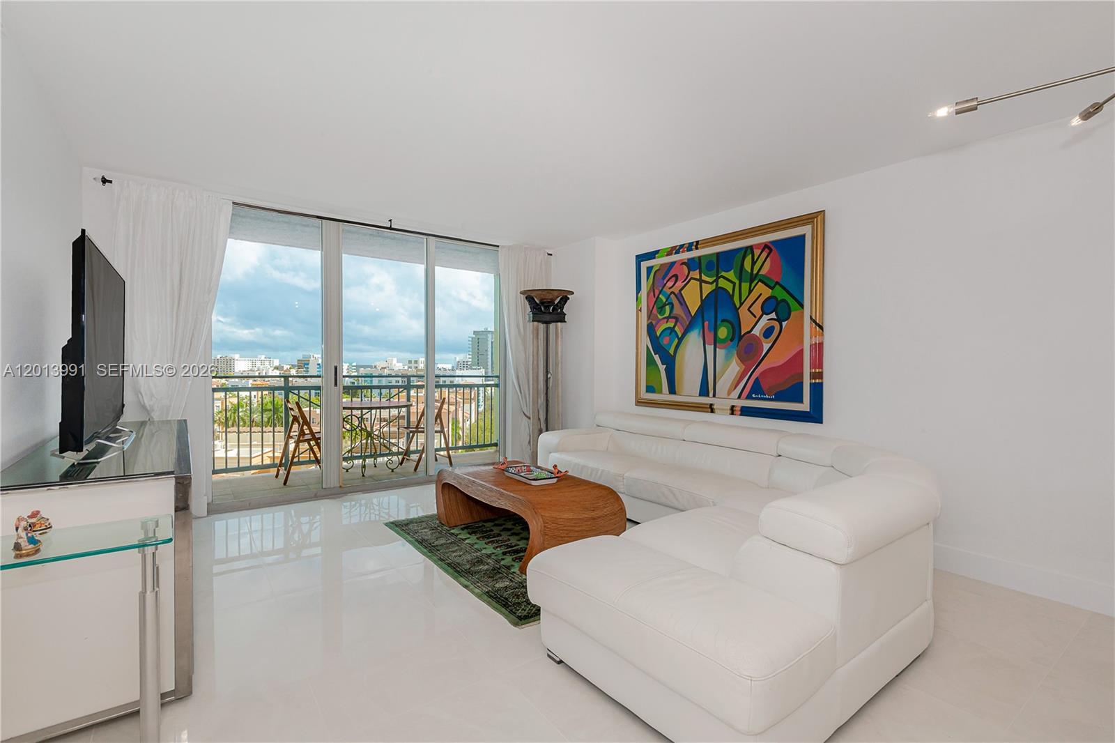 A living room features a white sectional sofa, wooden coffee table, and a balcony view — 90 ALTON RD # 1007, Miami Beach FL 33139, MIAMI BEACH, FL