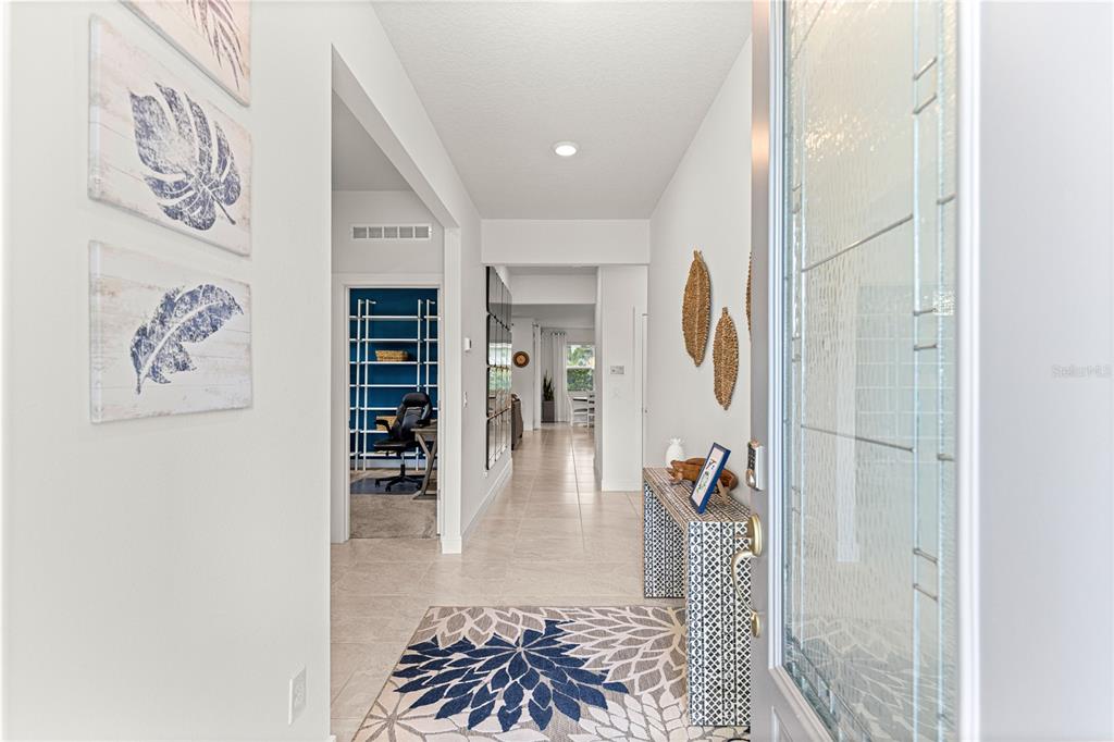 A bright entryway features tiled floors, a patterned rug, a console table, and wall art — 9295 SW 60TH LANE ROAD, OCALA, FL