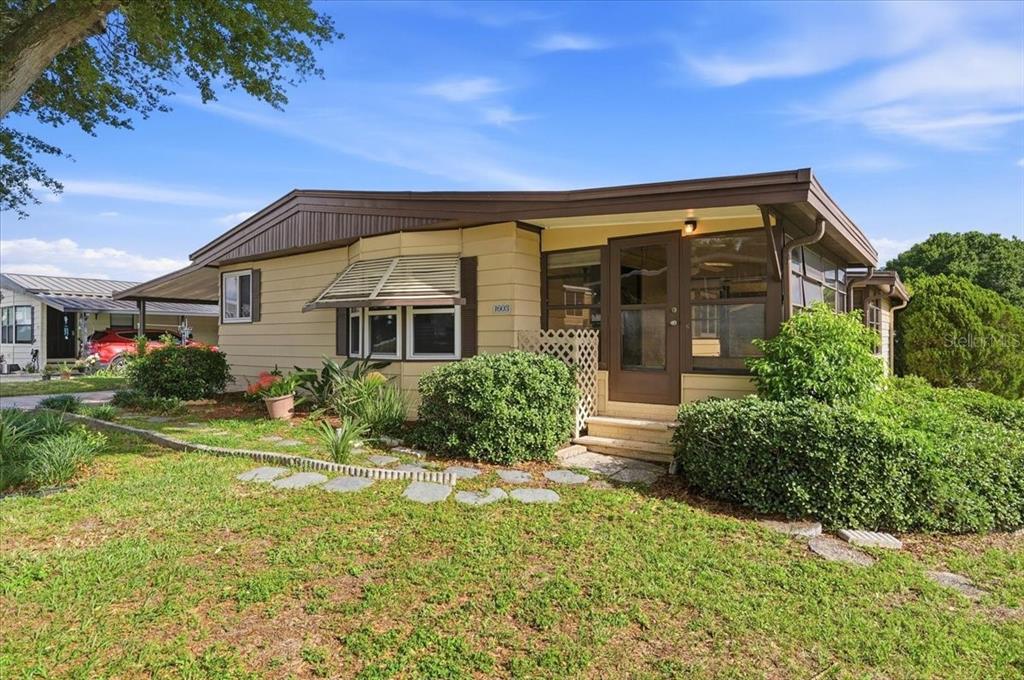 A single-story tan mobile home with a brown roof and a screened-in front porch — 1603 FOXWAY DRIVE, LAKELAND, FL