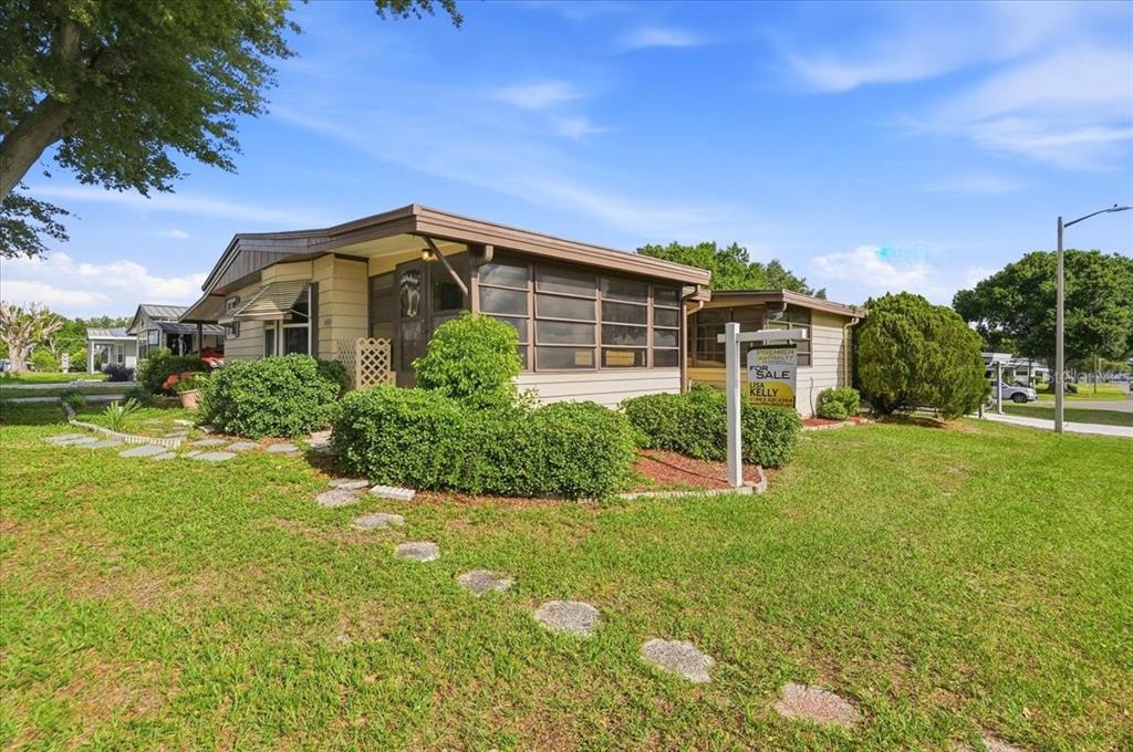 A single-story mobile home with a screened-in porch sits on a grassy lot — 1603 FOXWAY DRIVE, LAKELAND, FL