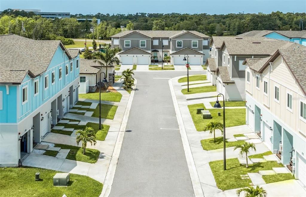 An aerial view of a residential street lined with modern multi-story townhomes and palm trees — 2058 SILVERSTONE CIRCLE, CLEARWATER, FL