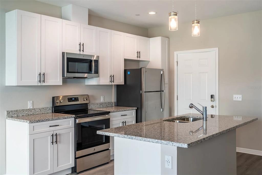 A kitchen with white cabinets, stainless steel appliances, granite countertops, and a central island — 2058 SILVERSTONE CIRCLE, CLEARWATER, FL