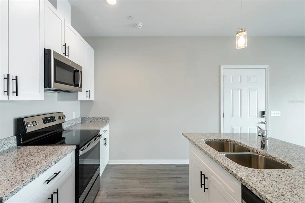 A kitchen features white cabinets, granite countertops, stainless steel appliances, and a central island — 2058 SILVERSTONE CIRCLE, CLEARWATER, FL