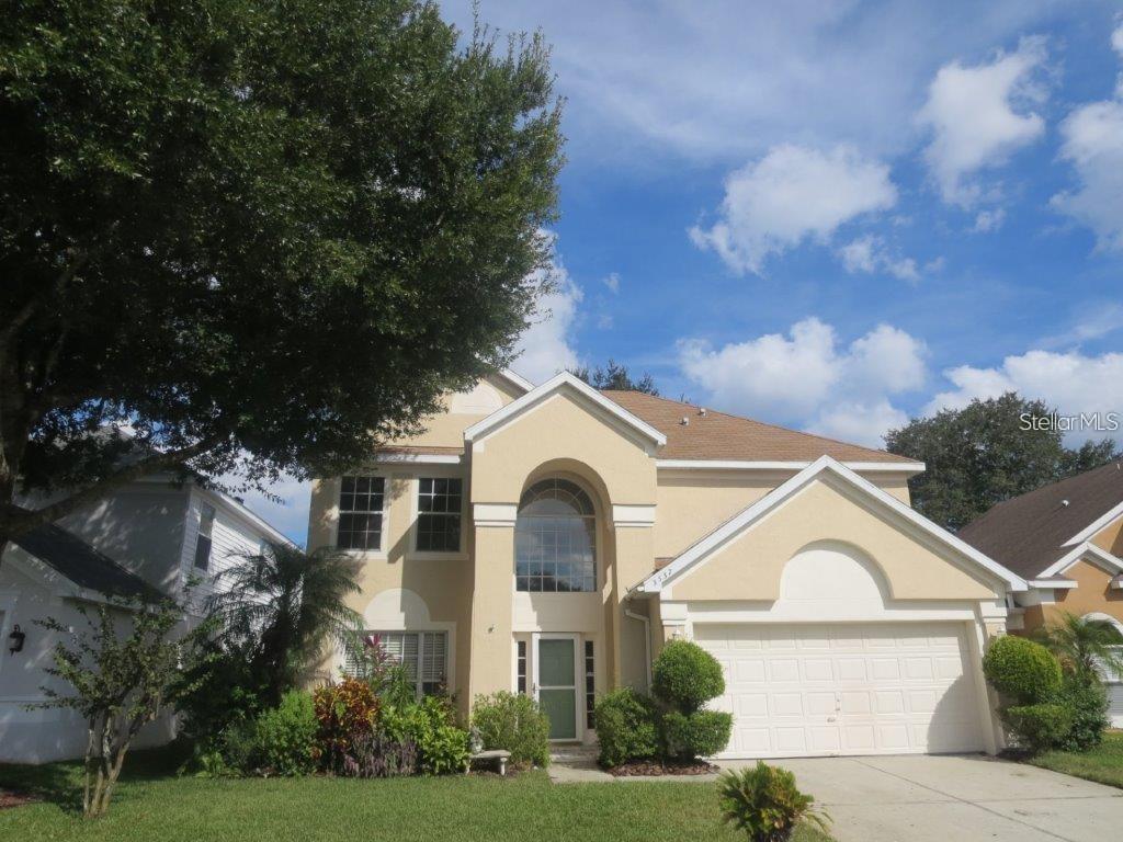 A two-story suburban house with a beige stucco exterior, arched entryway, and attached garage — 3537 MOSS POINTE PLACE, LAKE MARY, FL