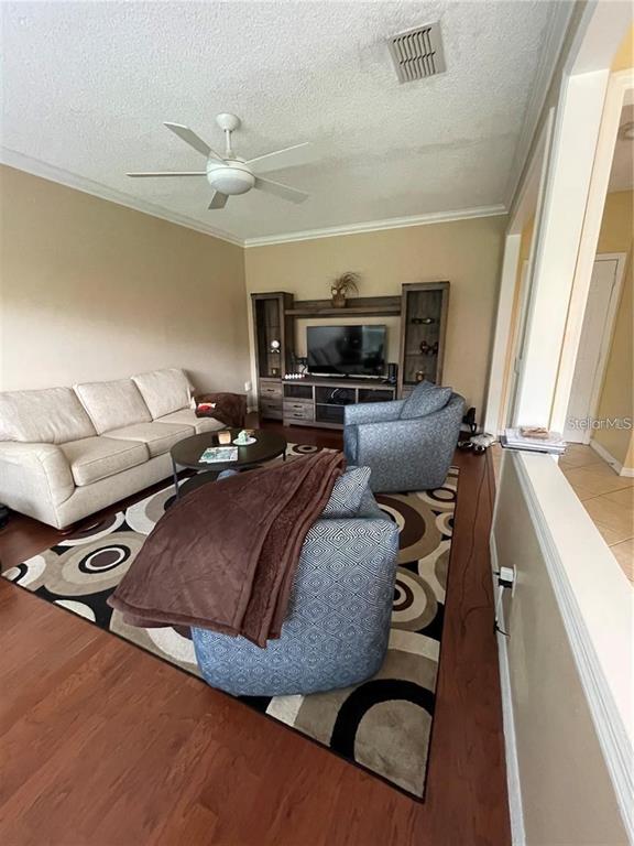 A living room features a beige sofa, two patterned armchairs, and a wood entertainment center — 3537 MOSS POINTE PLACE, LAKE MARY, FL