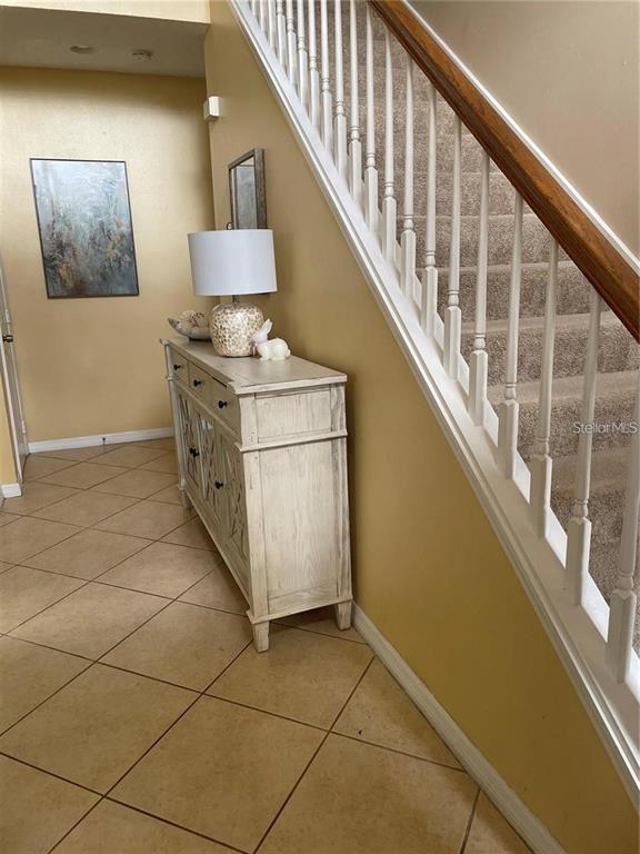 A foyer features a white wooden console table, a lamp, and a carpeted staircase — 3537 MOSS POINTE PLACE, LAKE MARY, FL