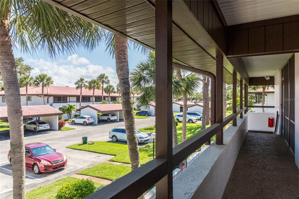A view from a covered balcony overlooking a parking lot with palm trees and cars — 3500 EL CONQUISTADOR PARKWAY UNIT 268, BRADENTON, FL