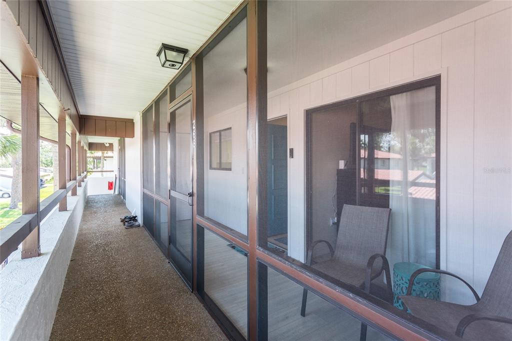 A covered, screened-in balcony features a concrete floor, brown framing, and outdoor seating — 3500 EL CONQUISTADOR PARKWAY UNIT 268, BRADENTON, FL